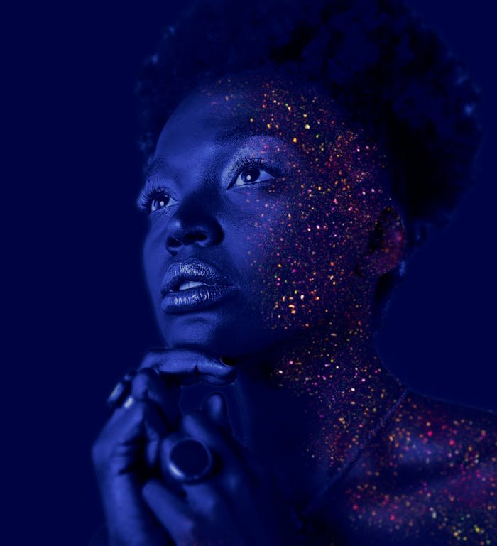 Mesmerizing portrait of a woman with glitter makeup and dramatic lighting.