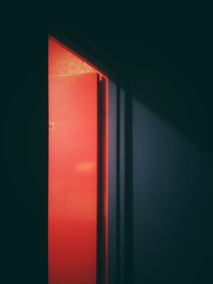 A captivating image of an open door illuminated by a neon red light, creating a sense of mystery.